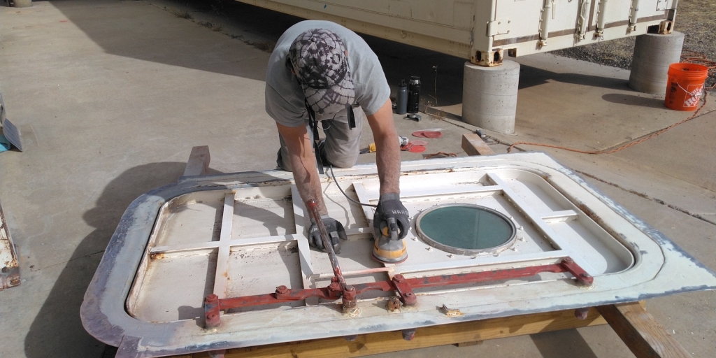 Nathan Schmit sands the third pressure door at SAM, Biosphere 2