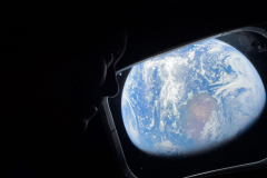 art002e008486 (April 4, 2026) - NASA astronaut and Artemis II Commander Reid Wiseman peers out of one of the Orion spacecraft's main cabin windows, looking back at Earth, as the crew travels towards the Moon.